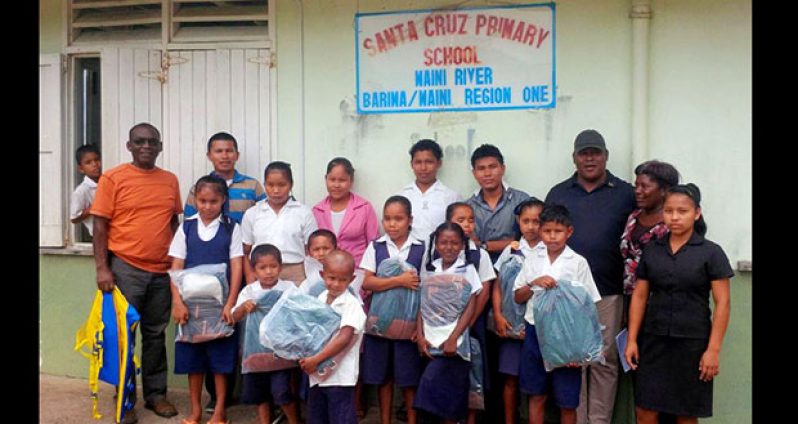 Students of the Santa Cruz Primary School pose with supplies they received via Guyana Aid Region One. Also in photo is Regional Executive Officer (REO) Leslie Wilburg. Third left is Regional Chairman Brentnol Ashley