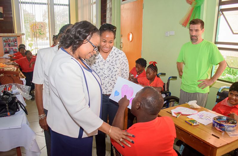 A student enthusiastically shows one of his drawings to Minister of Public Health, Volda Lawrence and Director of Disability and Rehabilitation Services, Ariane Mangar during her visit at the Ptolemy Reid’s Rehabilitation center on Wednesday [Samuel Maughn photo]