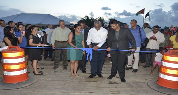 President David Granger participating in the symbolic ribbon-cutting ceremony for the commissioning of the GAICO Wharf Facility and Trailing Suction Hopper Dredge as well-wishers look on