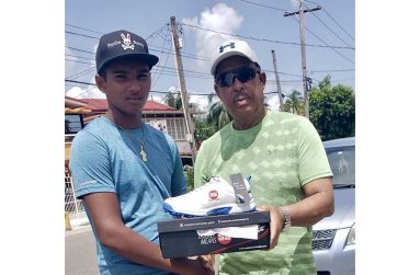 Richard Sewmangal, left, receives cricket shoes from Hubern Evans