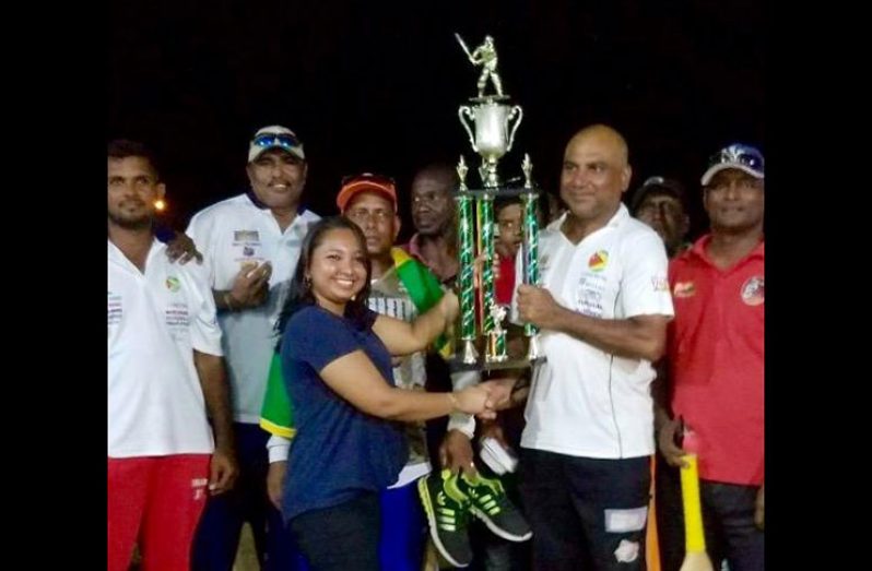 A smiling Floodlights skipper Ricky Deonarine receives the winning trophy from a representative of Permaul Trading while other members of the team look on.