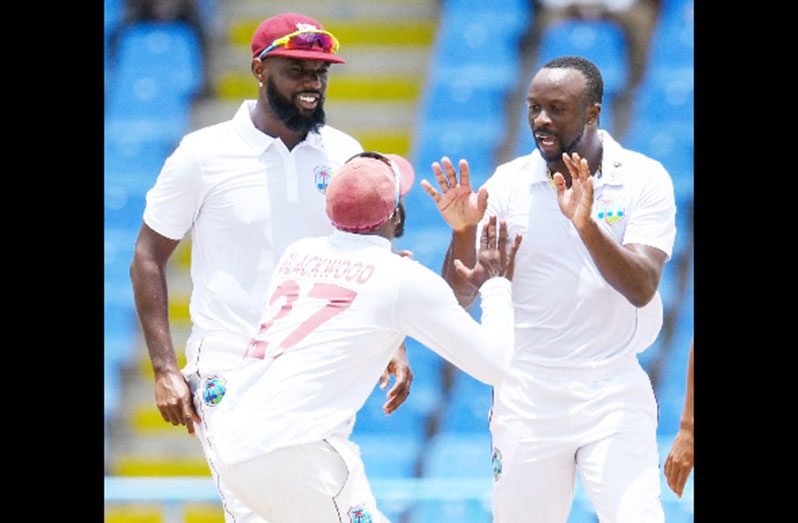 Seamer Kemar Roach (right) celebrates a wicket on Saturday with Jermaine Blackwood and Raymon Reifer (left)
