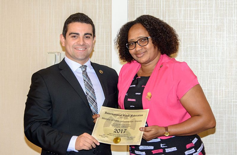 Minister within the Ministry of Public Infrastructure, Annette Ferguson, receives an International Road Federation (IRF) membership certificate from IRF Director, Esteban Salinas (Samuel Maughn Photo)