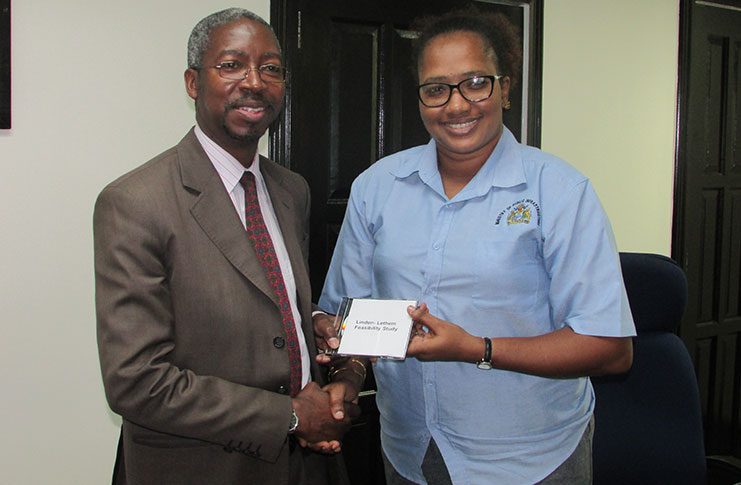 Minister within the Ministry of Public Infrastructure, Annette Ferguson (right) presents the Linden-Lethem Feasibility Study to Mr. Idrissa Dia of the Islamic Development Bank