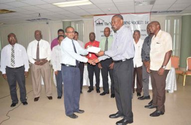 NBS Chief Executive Officer Anil Kishun hands over the sponsorship cheque for the GCA 40-over second division tournament to GCA president Roger Harper in the presence of other officials.