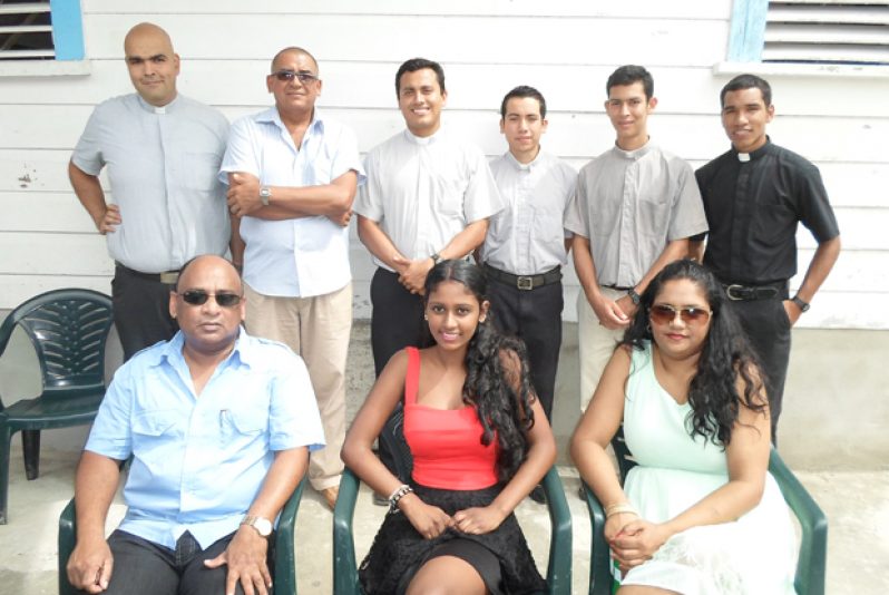 “We’re solidly behind you,” this photo seems to say. Director of Comfort Sleep, Mr. Dennis Charran; his wife, Mrs. Sabita Charran, and daughter Nakita pose with Priests of the Roman Catholic Diocese at the kids Christmas Treat at Malgre Tout R.C. Church compound.