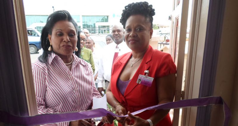 Mrs. Yvonne Hinds, wife of Prime Minister Samuel Hinds, officiates at the ribbon cutting ceremony. At right is CEO Yvette Irving