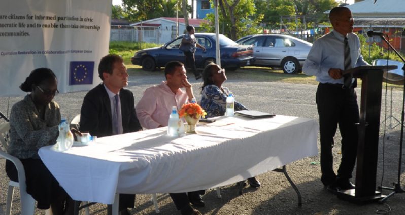 Rev. Simon Harris addressing the gathering at the launch of ‘East Ruimveldt Cooperating for Community Transformation Project’ last Friday. From left at the head table are Ms. Donna Collier; Head of Co-operation, European Union Delegation to Guyana, Mr. Ewout Sandker;  Permanent Secretary in the Ministry of Local Government, Mr Collin Croal; and Chairperson, Ms. Lyris Primo