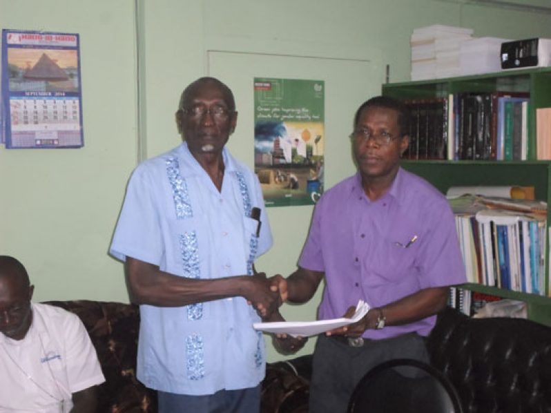 Mr. Michael Carter of COURTS presents a copy of the agreement to Francis Carryl, Labour Consultant