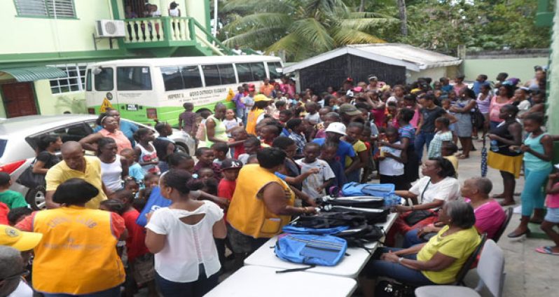 Lions Club members distribute backpacks to the children of Albouystown