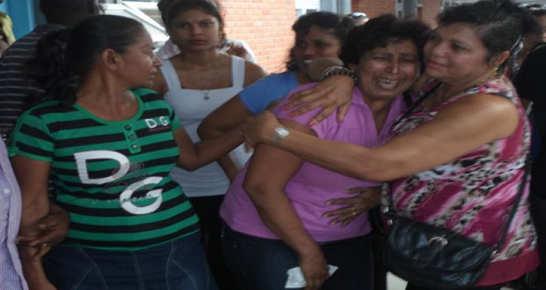 Jai’s sister Seeta (second from right) weeps bitterly whilst being consoled by another family member.