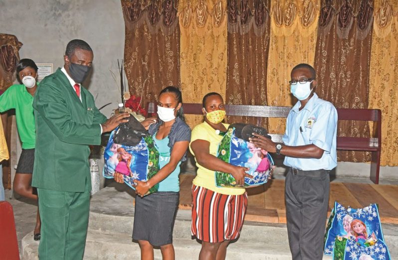 Pastor Andrew Chichester, the Community Services Director of the Guyana Conference of Seventh-day Adventists assisting with the distribution of packages, along with another member of the church during a donation of hampers to residents in Angoy’s Avenue, New Amsterdam Berbice earlier this month