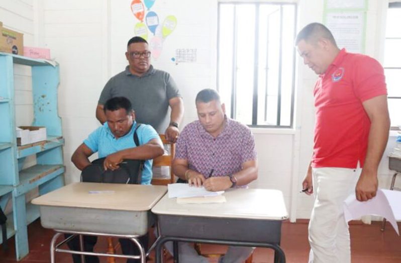 Minister of Housing and Water Collin Croal (seated right) inks one of the contracts awarded for the construction of new houses at Smith Creek, Region One (DPI photo)