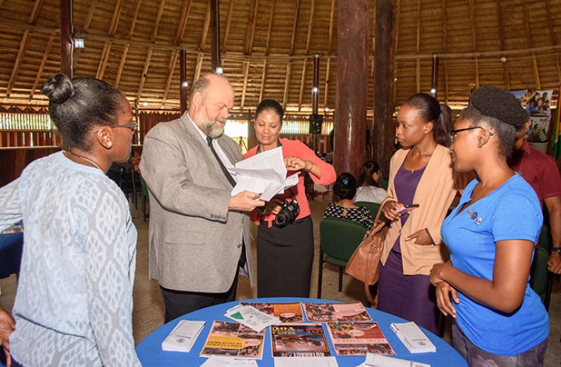 US Ambassador, Perry Holloway and Public Affairs Assistant of the US Embassy, Aretha Majeed (centre) peruse one of the booths set up at the Youth Exposition and Volunteer Fair at the Umana Yana, Kingston, Georgetown. [Samuel Maughn photo]