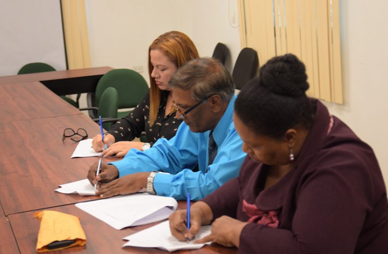 Demerara Mutual staffers affixing their signatures to the approved document