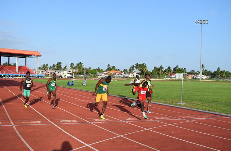 Akeem Stewart (second right) dips across the finish line to win the Men’s 100m gold.