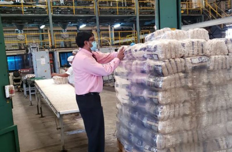 GuySuCo Chief Executive Officer (ag), Sasenarine Singh, assisting in packing the first batch of packaged sugar at the Enmore packaging facility