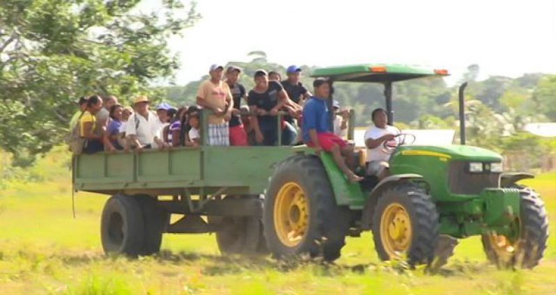 Residents of Semonie, Region 9, being transported via a tractor and trailer which were provided to the community through a presidential grant.