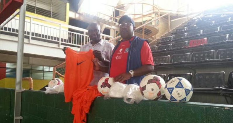 Former Technical Director of the Guyana Football Federation Jamal Shabazz (right) assists Aubrey ‘Shanghai’ Major in displaying one of the bibs while the remaining bibs and balls are in front of them.