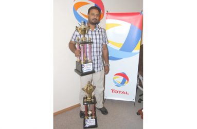 Shairaz Roshandin poses for Chronicle Sport photographer Sonell Nelson with two of his many trophies yesterday. (Rawle Toney)