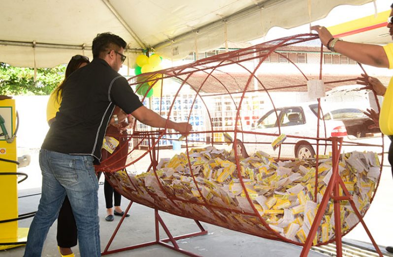 A member of the public pulls a name from the rotisserie at the draw held 

at the Lowe’s Service Station, Vlissengen Road, Bel-Air Park on Wednesday (Adrian Narine photo)