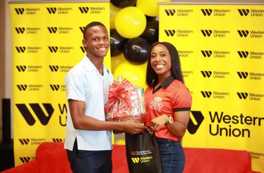 Champs double-silver medalist Luke Plummer of Sydney Pagon STEM Academy presents a gift basket to GraceKennedy Ambassador Shelly-Ann Fraser Pryce during their Future Champions initiative on Friday