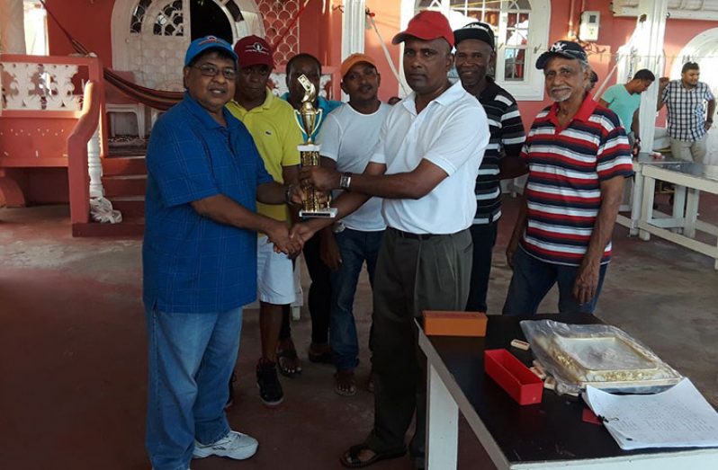 Cold Fusion skipper and Superintendent of Police, Boodnarine Persaud, at right, hands over the winning trophy to International 6 captain Manniram Shew on behalf of the sponsors, Jeet brothers of USA.