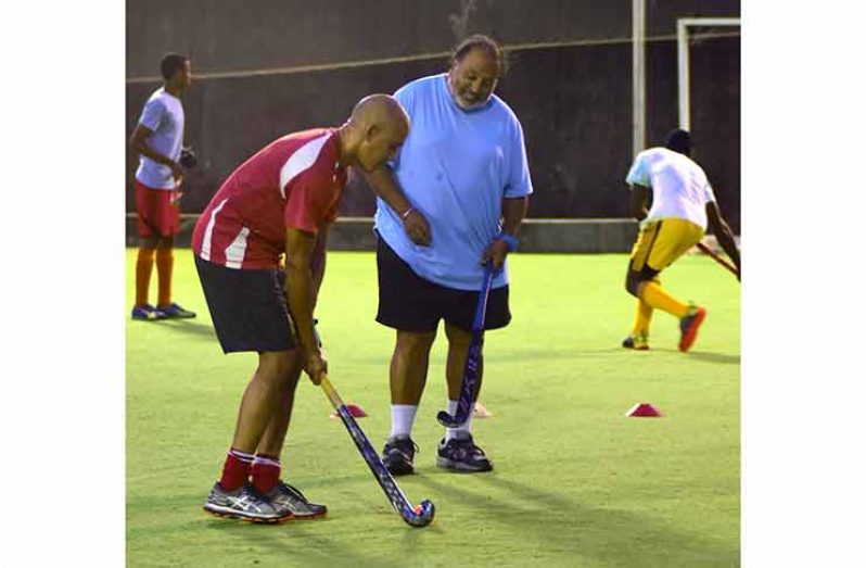 FIH coach Shiv Jagday guides a player through his paces on the artificial turf, at GCC. (Adrian Narine photo)