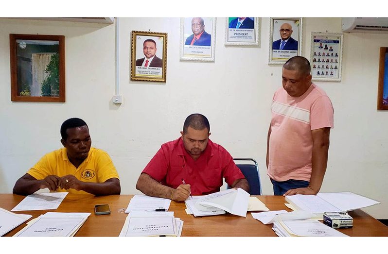 Regional Executive Officer (REO) Karl Singh signs a contract as the contractor looks on