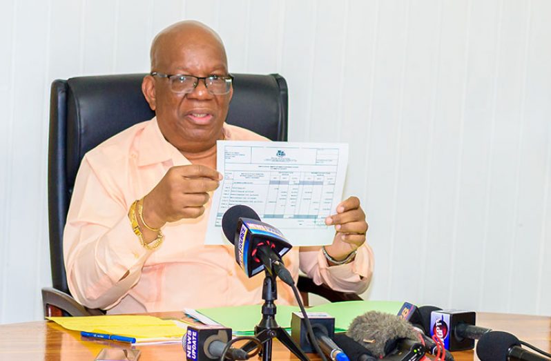 Finance Minister Winston Jordan displays the Central Bank statement on the signing bonus on Friday (Delano Williams photo)