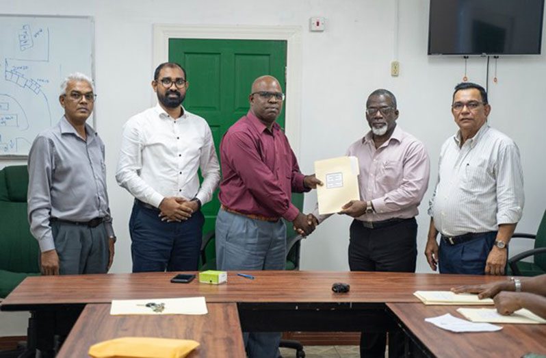 NAACIE’S General President, Whitney Graham, hands over a signed agreement to GPL’s Acting Chief Executive Officer, Renford Homer