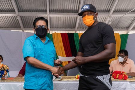 Senior Minister in the Office of the President with responsibility for Finance, Dr. Ashni Singh, presents a cheque to cash crop farmer, Oliver Giddings (DPI photo)
