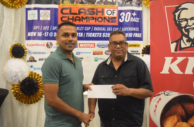 Darsho Singh (right) hands over Sankar’s sponsorship to the Guyana Motor Racing and Sports Club’s Motilall Deodas..
