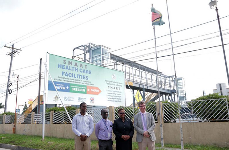 From left, British High Commissioner Greg Quinn; Public Health Minister Volda Lawrence; PAHO/WHO Country Representative Dr. Williams Adu-Krow; and the Regional Health Officer (Region Four) Dr. Quincy Jones, standing in front of the Smart Healthcare Facilities’ billboard.
