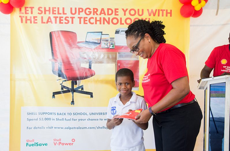 Sol’s Ayanna Watson hands over a prize to seven-year-old Christian Munroe of Marian Academy