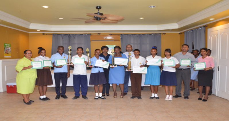 Guyana Lottery Company General Manager Tracy Lewis (Centre rear) flanked by students and representatives of the various schools which were awarded certificates, cash vouchers and trophies