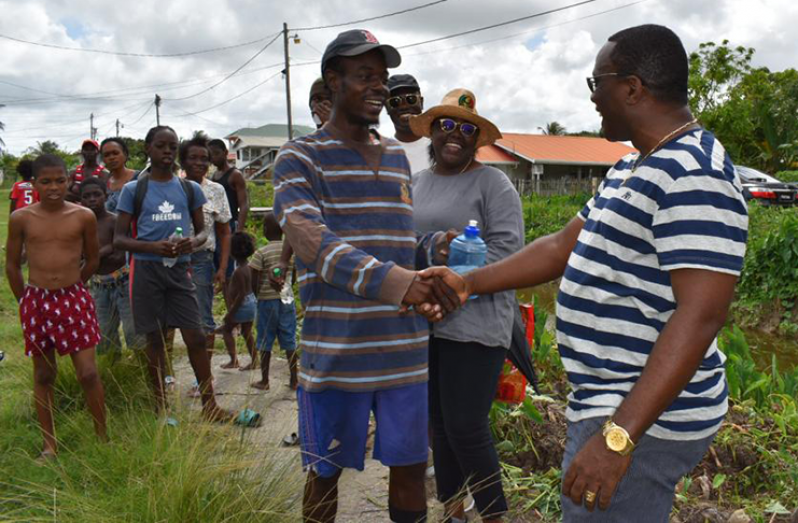 Deputy Commissioner of Police Paul Williams greeting one of the residents of Sophia upon his arrival in the area on Saturday
