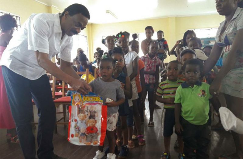 A surprised young girl receives her gift from Attorney General and Minister of Legal Affairs, Basil Williams,while other children wait in line to receive theirs