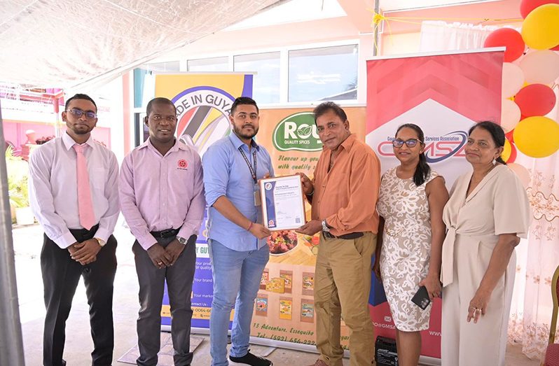 Caption: General Manager of Roy’s Extra Quality Products, Mr. Lakiraj Singh receives the Made- in-Guyana Certificate from GNBS Technical Officer, Mr. Latchman Mootoosammi. Also, in photo are (L-R) Marketing/Sales Manager of Roy’s Extra Quality Products Mr. Govinda Singh, GNBS Head of Corporate Communications, Mr. Lloyd David, and others.