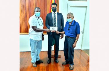 GCF president Linden Dowridge (left) and organiser Hassan Mohamed (right) flank Minister of Culture, Youth and Sport, Charles Ramson Jr, during the simple presentation.
