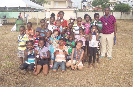 Winners of the Lamaha Springs Easter Fun Day kids’ competitions with the event’s coordinator, Ms Jennifer Younge