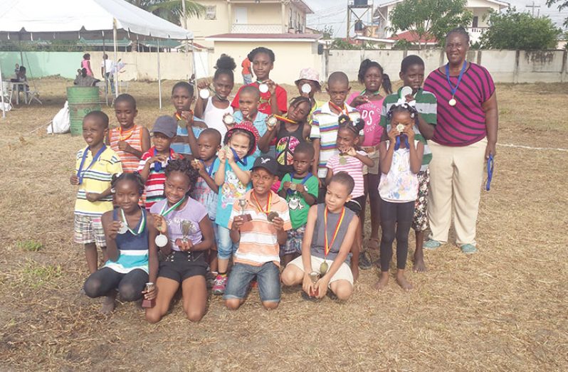 Winners of the Lamaha Springs Easter Fun Day kids’ competitions with the event’s coordinator, Ms Jennifer Younge