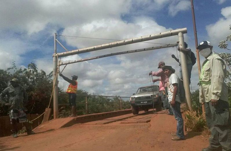 Workmen erecting a gate at the entrance of a bridge which leads to St Ignatius from the town of Lethem. (Mark Rodrigues photo)