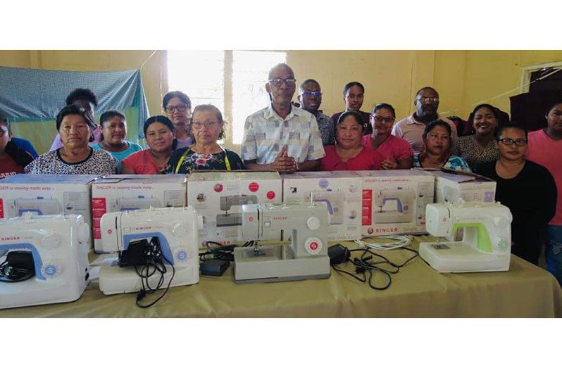 Minister of Labour, Joseph Hamilton (center), BIT’s CEO, Richard Maughn (behind Minister Hamilton) flanked by the Garment Construction trainees in St. Ignatius Village and the new sewing machines that were donated