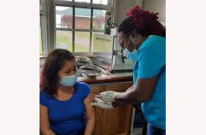 An Iwokrama staffer receiving her vaccine from a member of the MoH outreach team at the Iwokrama River Lodge, Kurupukari, Essequibo River