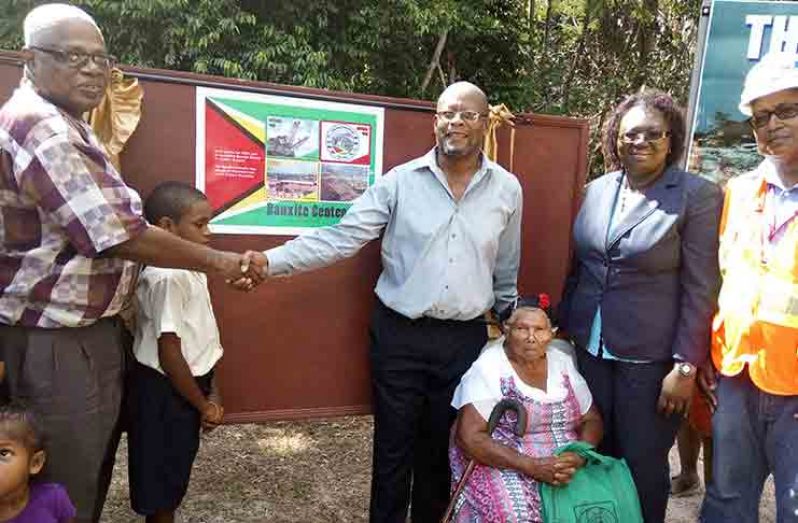 The four centennial stamps unveiled by Chairman of the Centennial Committee Horace James (left), Public Telecommunications Ministerial Advisor Enricho Woolford, General Post Master Karen Brown, Bosai’s Chief Engineer Orin Barnwell (right). Also in photo are 86-year-old eah Lorimor (sitting), the oldest resident of Three Friends and a student of Coomacka Primary school