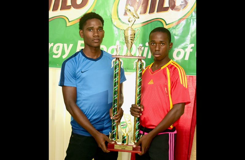 All or nothing! Sir Leon’s Shemar Carrington and Buxton’s Shemar Scott pose with the Milo 2018 trophy earlier this week. Only one team will take it home. (Adrian Narine photo)