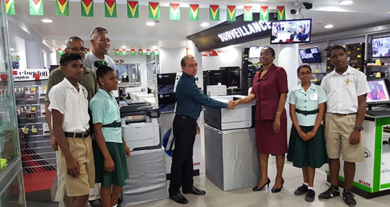 STARR Computer CEO, Mike Mohan officially hands over the equipment, seen in the background, to Deputy Headteacher, Allison Cosbert in the presence of alumni representatives Alex Neptune, Linden Branche and students