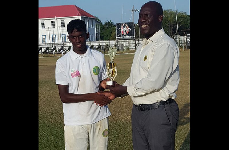 Man-of-the-match Pradeep Balkishun collects his trophy from Match referee Colin Stuart.