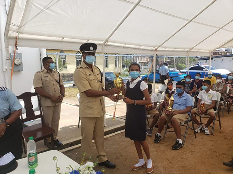 A Springlands Primary School pupil receives a trophy and a medallion from Commander Ramlakhan during the ceremony